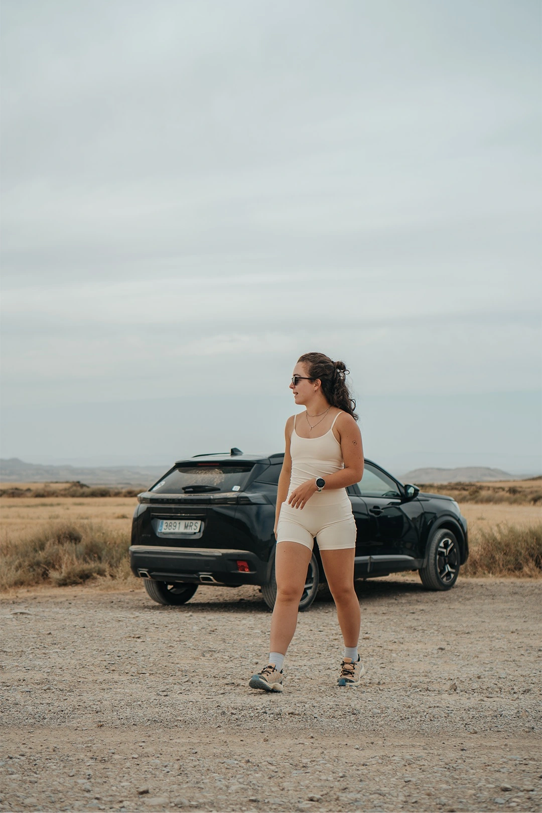 Britt beside a car in an open desert landscape